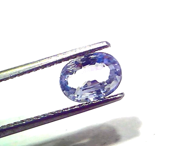 Oval-shaped 2.05 carat unheated natural Ceylon blue sapphire held by tweezers, showcasing its vibrant blue hue and brilliance