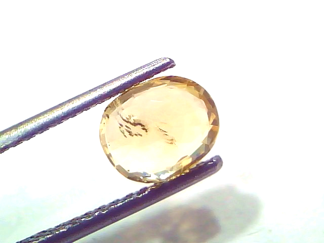2.14 Ct Certified Unheated Natural Ceylon Yellow Sapphire Pukhraj displayed in tweezers, showcasing its oval cut and vibrant