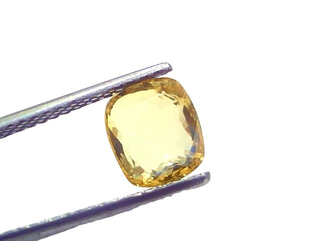 Cushion cut 3.05 ct natural Ceylon yellow sapphire held by tweezers, showcasing its VVS clarity and vibrant yellow hue.