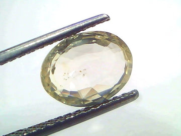 3.07 Ct Certified Unheated Natural Ceylon Yellow Sapphire Pukhraj displayed between tweezers, showcasing its oval cut and cla