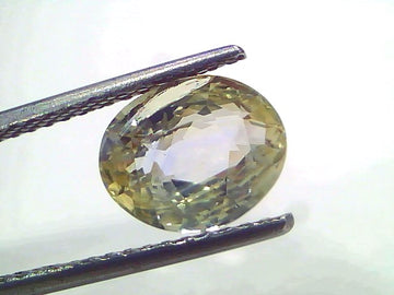 Oval-cut 3.65 Ct certified unheated natural Ceylon yellow-blue sapphire held by tweezers, showcasing its clarity and brillian