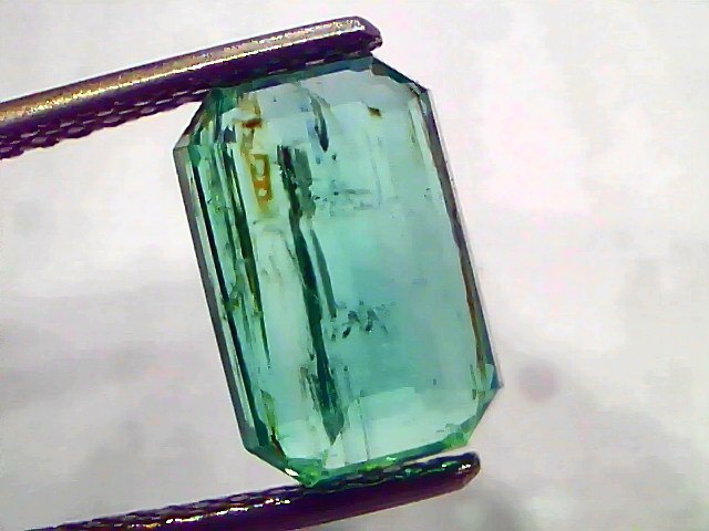3.76 carat certified natural Zambian emerald, untreated, with an octagonal cut and vibrant green color, held by tweezers.