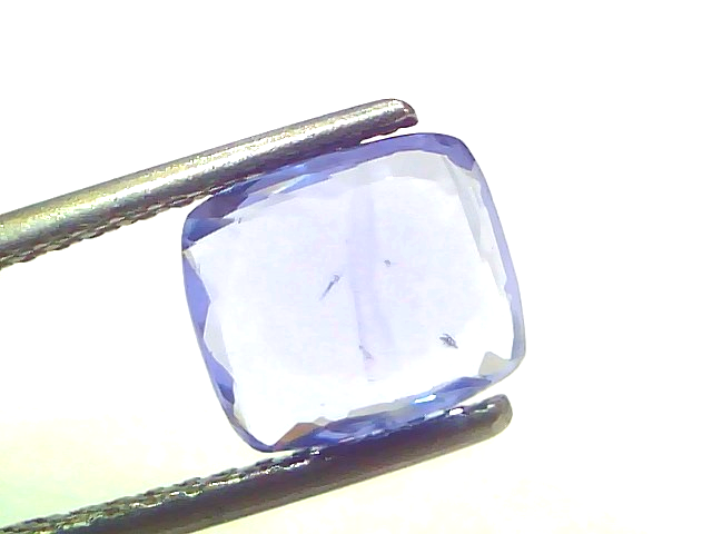 Ceylon blue sapphire gemstone, 3.03 carats, cushion cut, held by tweezers, showcasing its clarity and color.