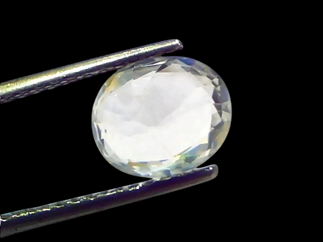 3.11 Ct Gii Certified Unheated Untreated Natural Ceylon White Sapphire, oval cut, held with tweezers against a light backgrou