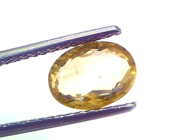 3.17 carat IGI certified unheated natural Ceylon yellow sapphire, oval shape, held with tweezers against a white background.