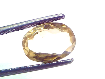 Oval-shaped yellow sapphire gemstone, 3.16 carats, unheated, held with tweezers against a light background.