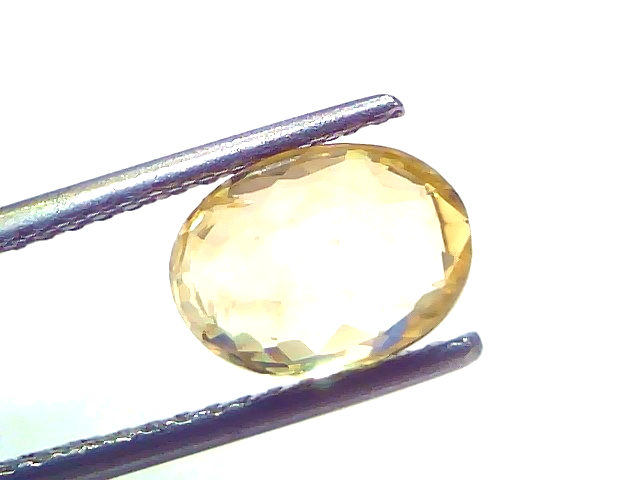 3.17 carat IGI certified unheated natural Ceylon yellow sapphire, oval shape, held with tweezers against a white background.