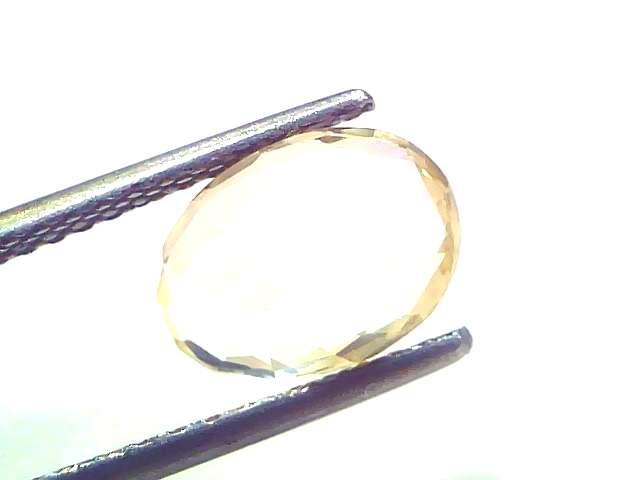 3.16 carat IGI certified yellow sapphire Pukhraj stone, unheated, displayed between tweezers against a white background.