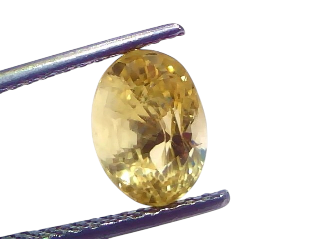IGI Certified 3.79 Carat Yellow Sapphire Pukhraj, unheated, oval-cut stone held by tweezers against a light background.