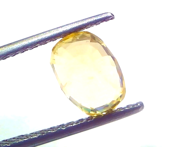 A 3.08 carat IGI certified yellow sapphire (Pukhraj) held by tweezers, showcasing its unheated, radiant cut and vibrant yello