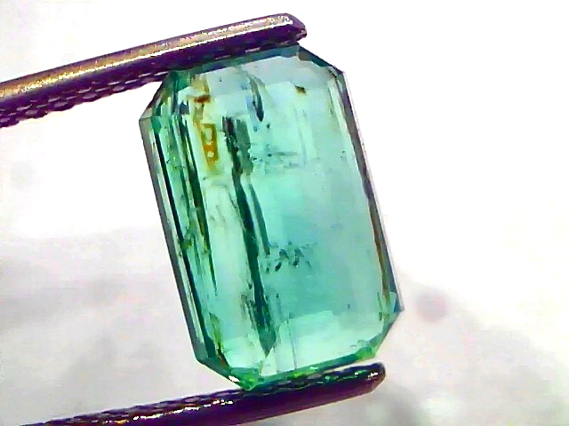 3.76 carat certified natural Zambian emerald, untreated, with an octagonal cut and vibrant green color, held by tweezers.