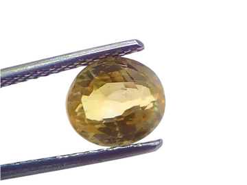 3.12 carat IGI certified yellow sapphire Pukhraj stone, unheated, displayed in tweezers against a light background.