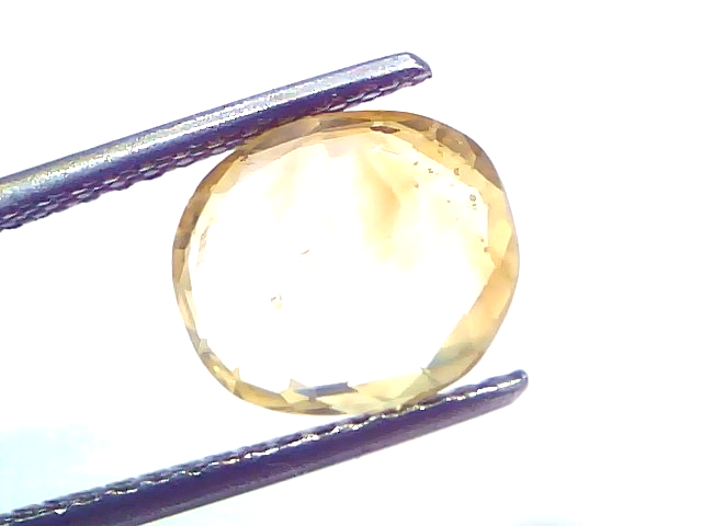 4.07 carat IGI certified unheated natural Ceylon yellow sapphire held by tweezers, showcasing its oval cut and clarity.