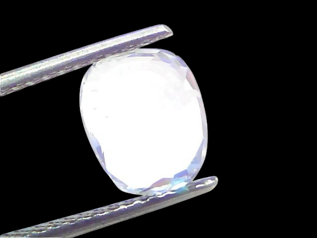 Venus Gems 4.09 carat natural cushion-cut white sapphire gemstone held in tweezers, showing clear VVS clarity.