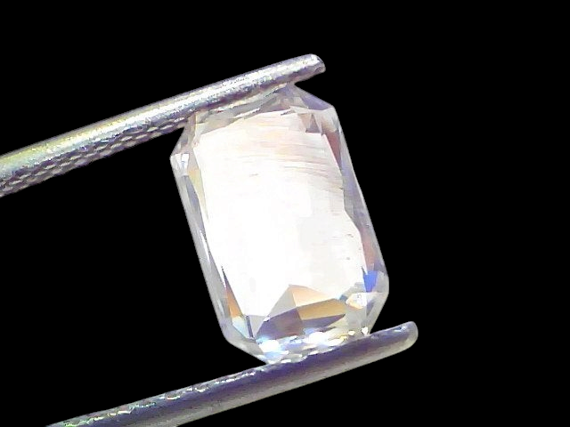 4.09 Ct Gii Certified Unheated Untreated Natural Ceylon White Sapphire, octagonal cut, held with tweezers against a light bac