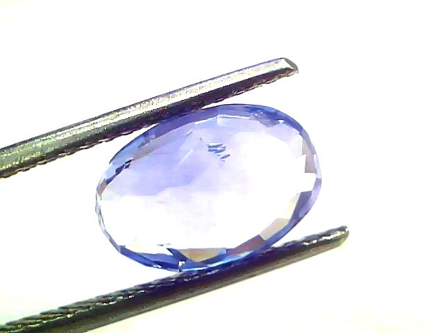 4.46 carat IGI certified unheated natural Ceylon blue sapphire in an oval cut, held with tweezers against a white background.