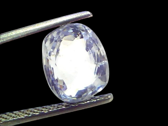 Venus Gems 4.09 carat natural cushion-cut white sapphire gemstone held in tweezers, showing clear VVS clarity.