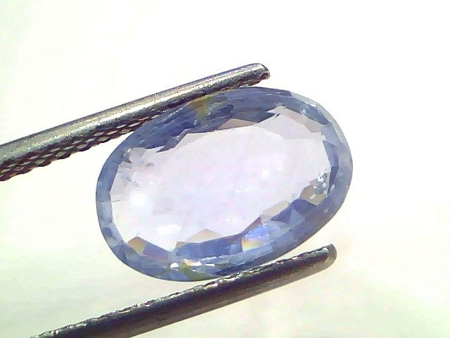 4.00 carat unheated natural Ceylon blue sapphire, oval cut, displayed with tweezers against a white background.