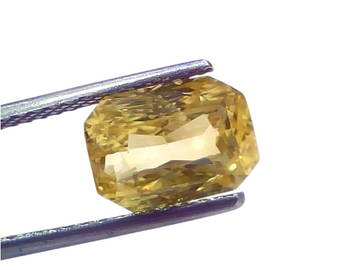 5.08 Ct IGI Certified Unheated Natural Ceylon Yellow Sapphire Pukhraj, octagonal cut, held by tweezers against a light backgr