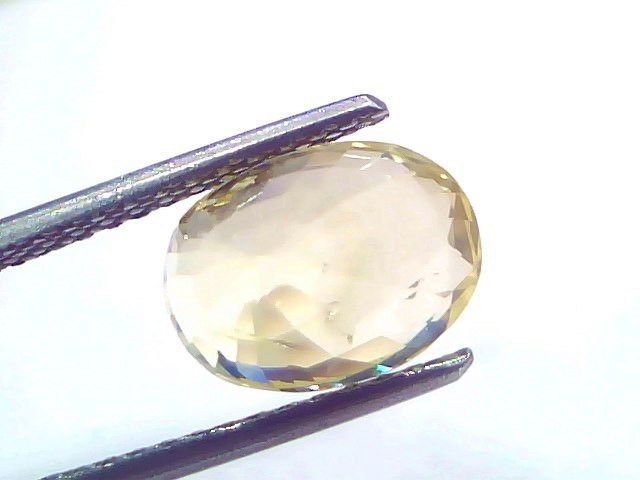 5.00 Ct IGI Certified Unheated Natural Ceylon Yellow Sapphire Pukhraj, oval-cut gemstone held with tweezers, showcasing its b