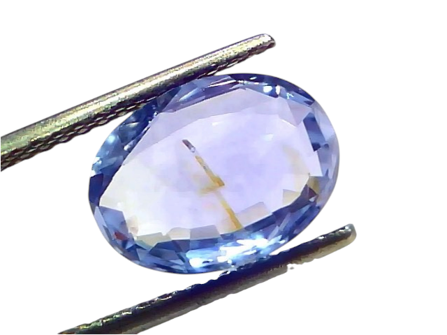 5.78 carat IGI certified unheated natural Ceylon blue sapphire, oval cut, displayed between tweezers on a white background.