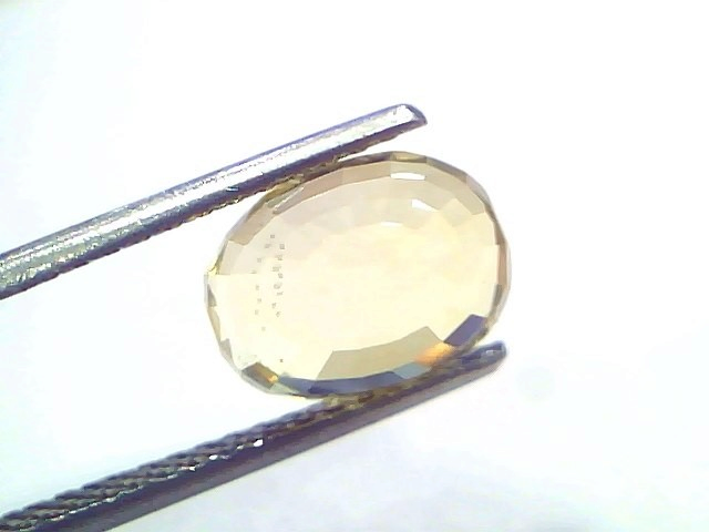 5.04 Ct IGI Certified Unheated Natural Ceylon Yellow Sapphire Pukhraj, oval-cut, held by tweezers, showcasing its vibrant yel