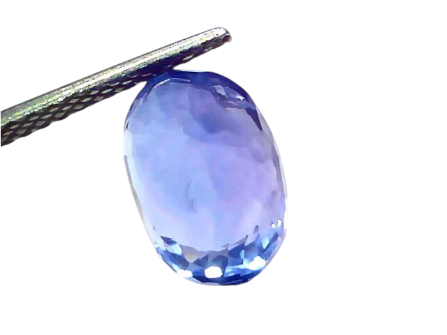 5.06 carat IGI certified unheated natural Ceylon blue sapphire, oval cut, displayed between tweezers against a light backgrou