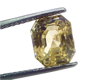 6.29 Ct IGI Certified Unheated Natural Ceylon Yellow Sapphire Pukhraj, octagonal cut with a golden hue, held by tweezers.