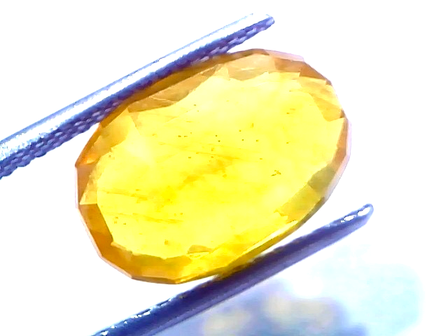 Natural yellow sapphire pukhraj stone, 7.48 carats, oval cut, heated, with a bright yellow hue and some inclusions.