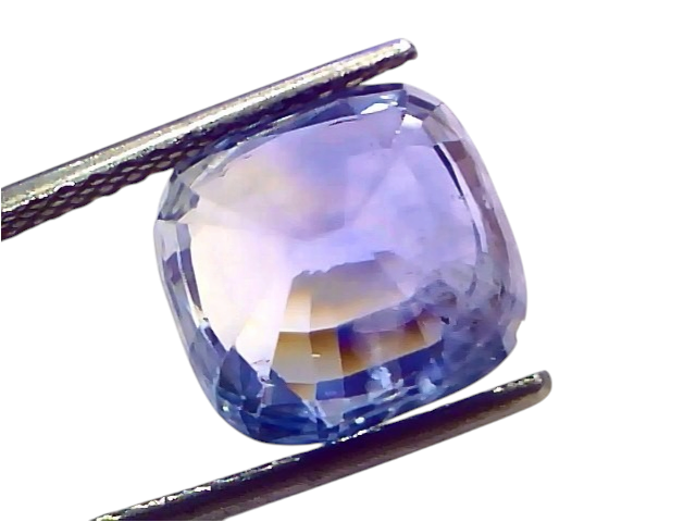 Ceylon blue sapphire gemstone, 9.53 carats, cushion cut, IGI certified, displayed in tweezers against a white background.