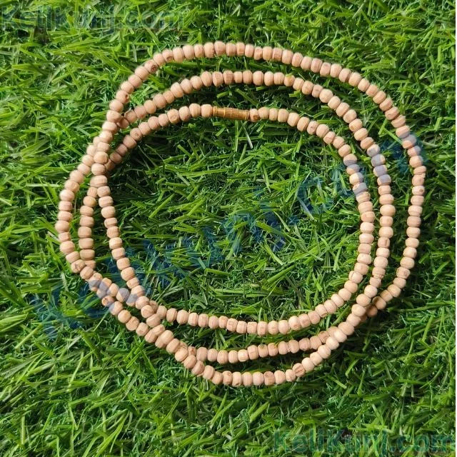 Natural Tulsi Mala from Venus Gems with 108 small beads, displayed on green grass for a serene look.